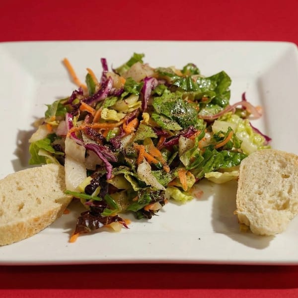 Fresh garden salad with mixed greens, shredded carrots, red cabbage, and two slices of bread.