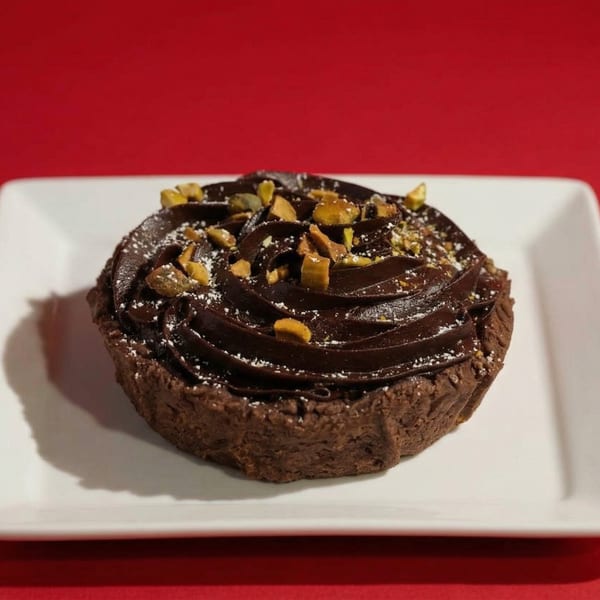 A chocolate tart with whipped chocolate ganache, topped with toffee bits and powdered sugar.